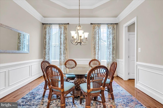 dining room featuring an inviting chandelier, plenty of natural light, a raised ceiling, and wood finished floors