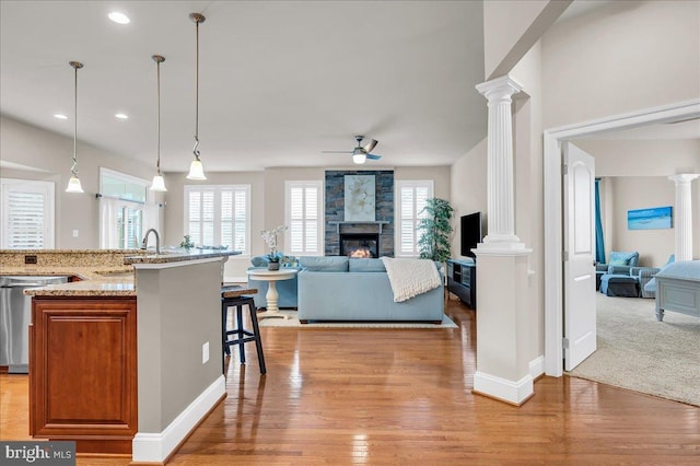 kitchen with ornate columns, open floor plan, a sink, and dishwasher