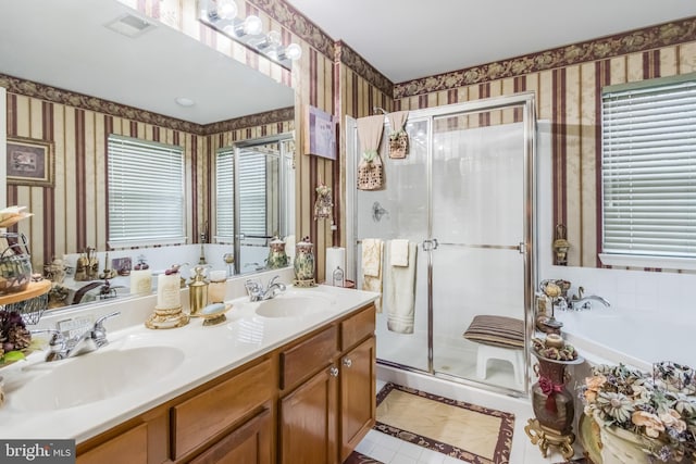 full bath with double vanity, wallpapered walls, a shower stall, and a sink