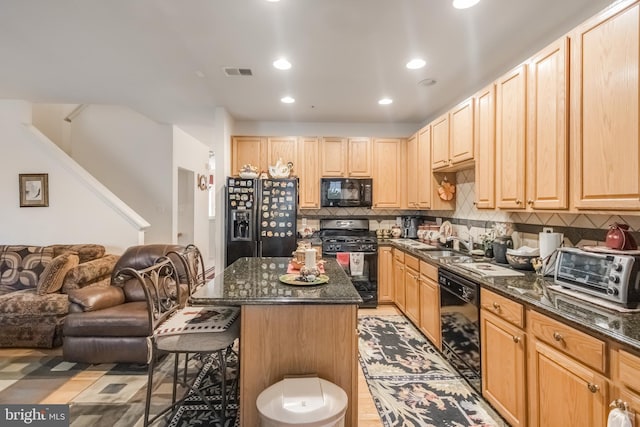 kitchen with visible vents, a breakfast bar, open floor plan, black appliances, and a sink