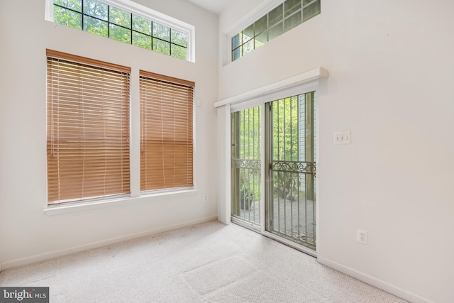 carpeted spare room with baseboards and a towering ceiling