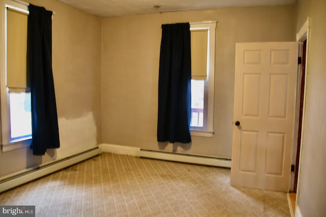 carpeted spare room featuring a baseboard heating unit and baseboards