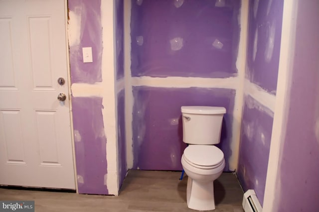 bathroom with baseboard heating, wood finished floors, and toilet