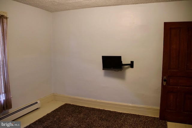 spare room with baseboards, baseboard heating, and a textured ceiling