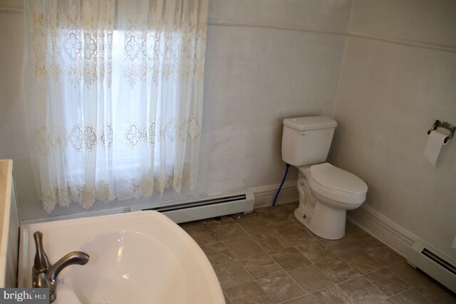 bathroom featuring baseboard heating and toilet