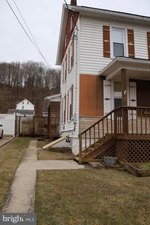 view of side of home featuring a chimney, a yard, and fence