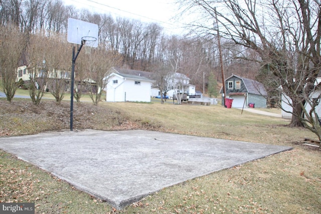 view of yard with a detached garage, an outdoor structure, and basketball hoop