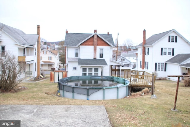 back of property featuring a covered pool, a residential view, and a lawn