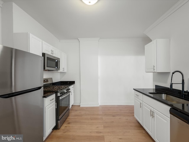 kitchen with ornamental molding, a sink, white cabinetry, stainless steel appliances, and light wood finished floors