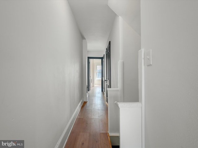 corridor featuring baseboards and hardwood / wood-style floors