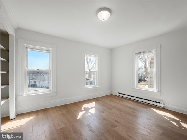 unfurnished room with plenty of natural light, a baseboard heating unit, and wood-type flooring