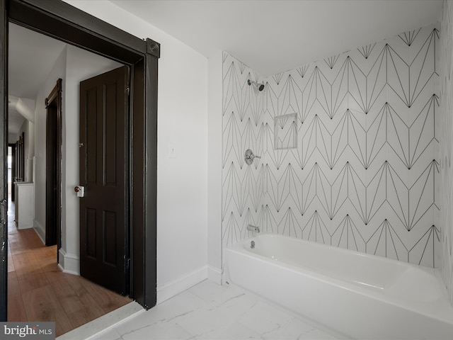 bathroom featuring baseboards, marble finish floor, and shower / washtub combination