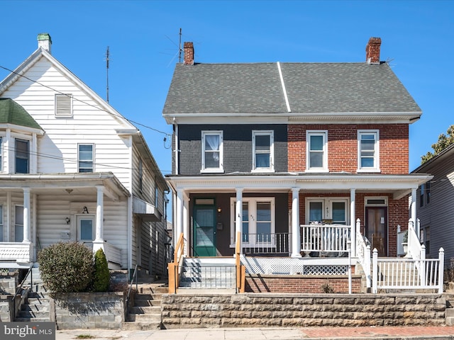 view of front of property featuring a porch, brick siding, and a chimney