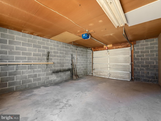 garage featuring a garage door opener and concrete block wall