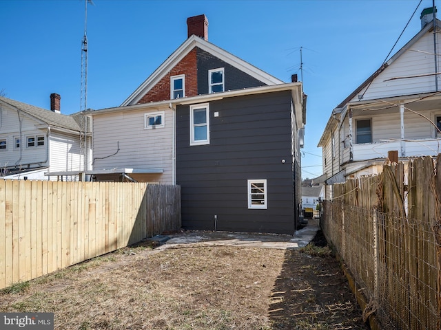 rear view of property featuring brick siding and fence