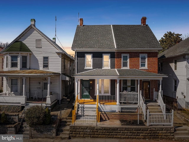 view of front of home with stairway, brick siding, covered porch, and a shingled roof