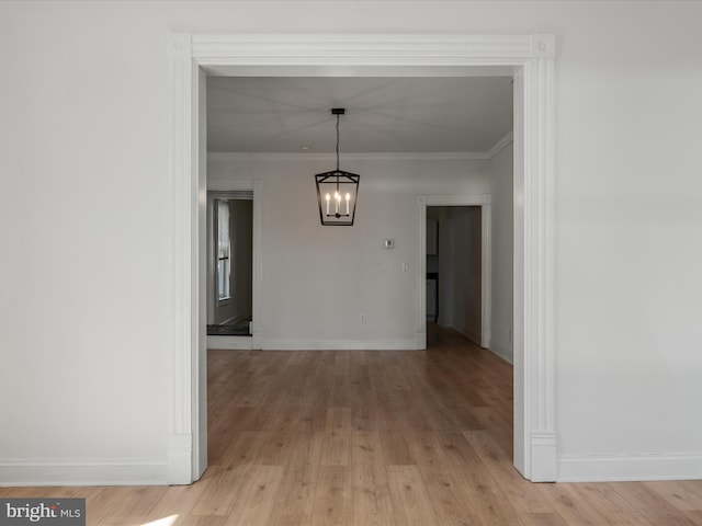 unfurnished dining area with light wood-type flooring, baseboards, and crown molding