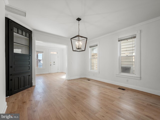 unfurnished dining area with visible vents, ornamental molding, light wood-style flooring, baseboards, and a chandelier