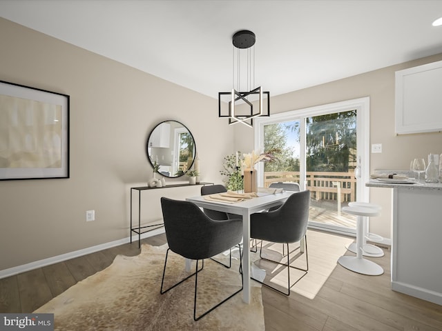 dining space featuring an inviting chandelier, baseboards, and light wood-style floors