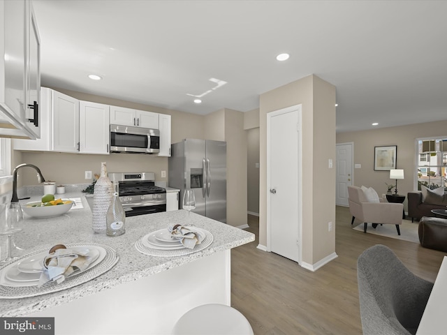 kitchen with light wood-style flooring, open floor plan, white cabinetry, recessed lighting, and appliances with stainless steel finishes