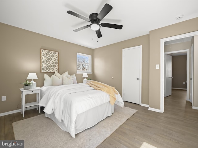 bedroom with attic access, wood finished floors, baseboards, and ceiling fan