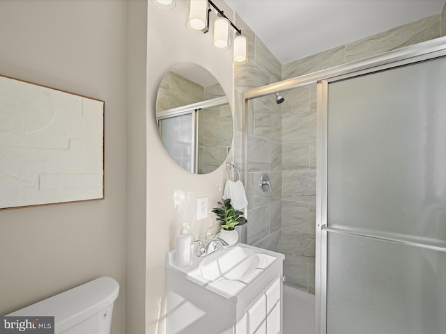 bathroom with vanity, toilet, and tiled shower