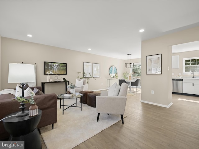 living room featuring light wood finished floors, plenty of natural light, recessed lighting, and baseboards