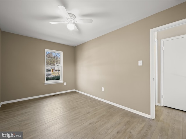 unfurnished room with ceiling fan, visible vents, baseboards, and wood finished floors