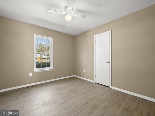 spare room with ceiling fan, wood finished floors, visible vents, and baseboards