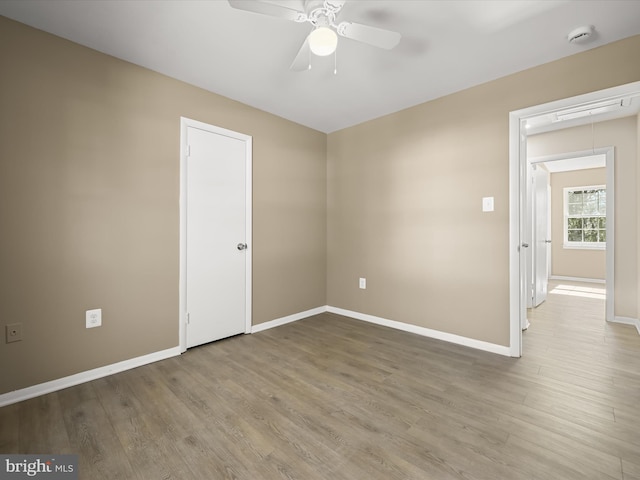 unfurnished room featuring ceiling fan, baseboards, attic access, and wood finished floors