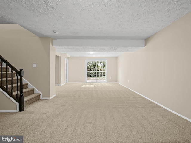 carpeted spare room featuring stairway, baseboards, and a textured ceiling