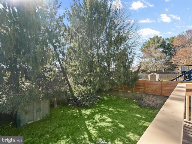 view of yard with an outbuilding, a storage unit, and a fenced backyard