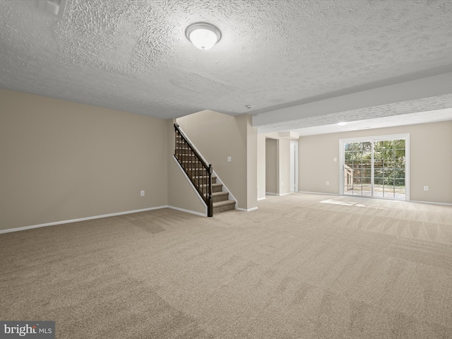 interior space with carpet flooring, stairway, a textured ceiling, and baseboards