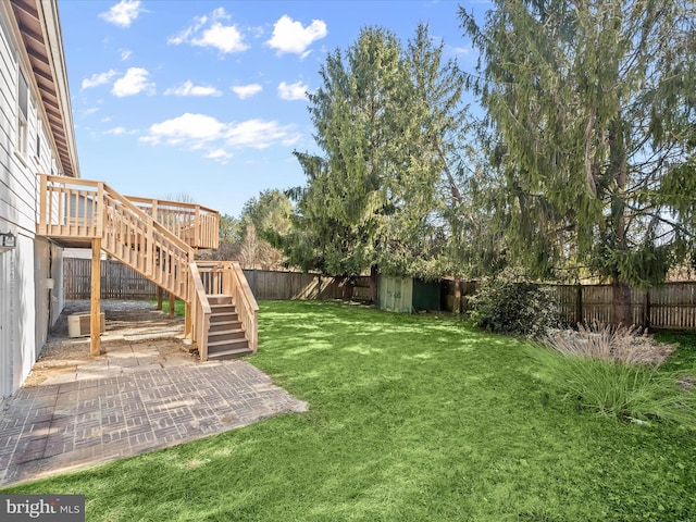 view of yard with a deck, central AC unit, stairway, and a fenced backyard