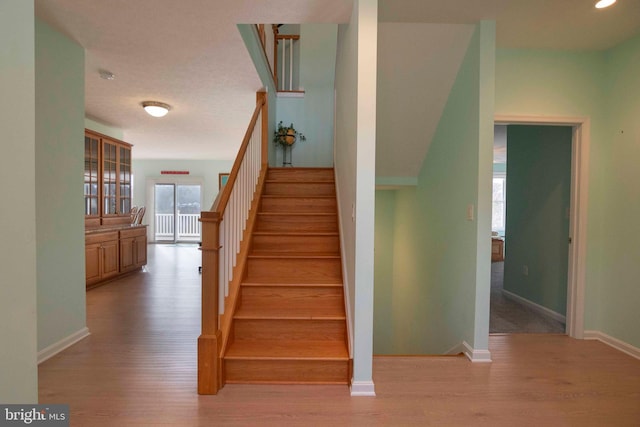 staircase featuring baseboards and wood finished floors