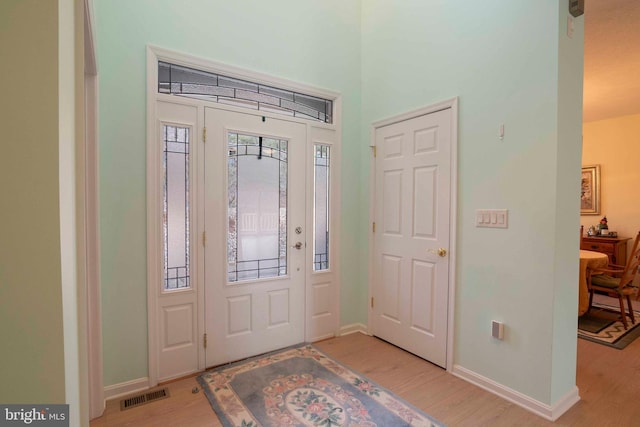 foyer with light wood-style floors, visible vents, and baseboards