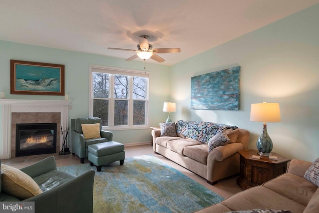 living area featuring a glass covered fireplace and ceiling fan