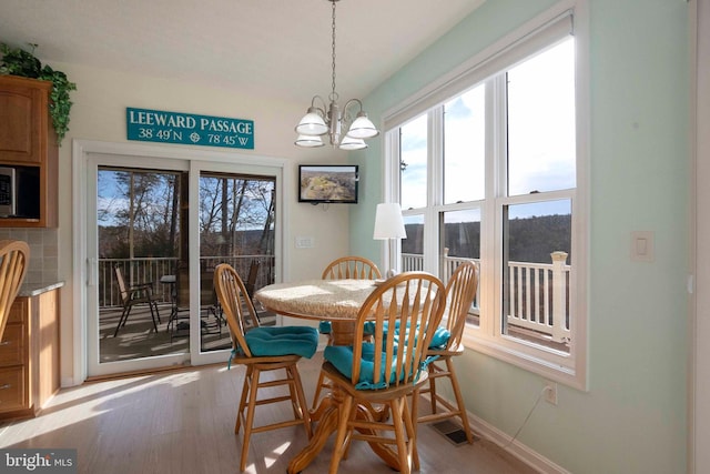 dining room with light wood-type flooring, an inviting chandelier, plenty of natural light, and visible vents