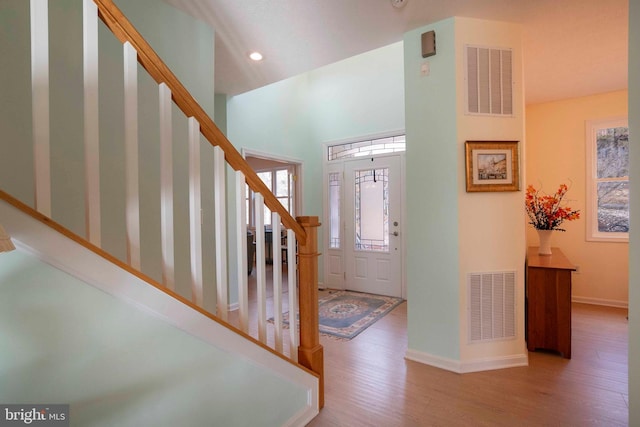 foyer with stairs, wood finished floors, visible vents, and baseboards