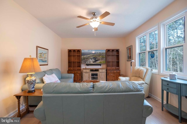 living room featuring ceiling fan, baseboards, and light wood-style floors