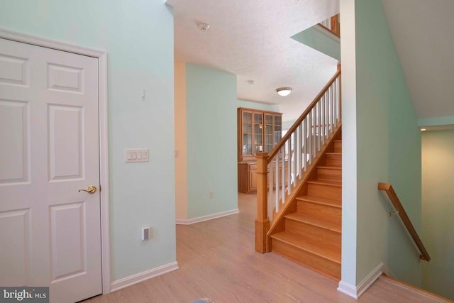 stairway featuring a textured ceiling, baseboards, and wood finished floors