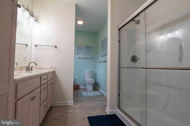 full bath featuring vanity, a shower stall, toilet, and baseboards