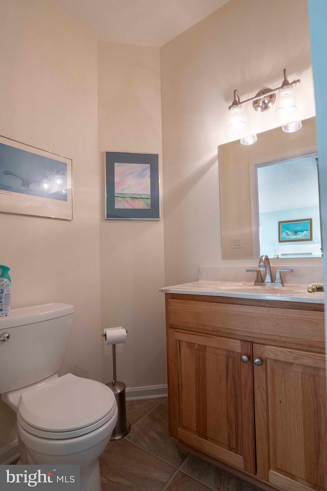 bathroom featuring tile patterned flooring, baseboards, vanity, and toilet