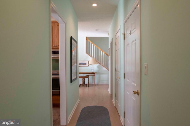 hall featuring stairs, baseboards, light wood-style flooring, and recessed lighting