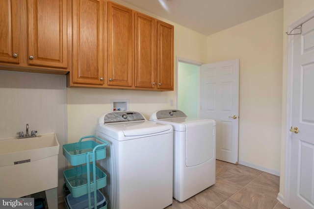 clothes washing area featuring cabinet space, a sink, washer and clothes dryer, and baseboards