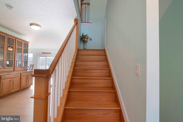 stairs with wood finished floors and baseboards