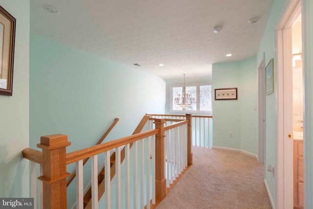 hallway with visible vents, carpet flooring, an upstairs landing, a chandelier, and baseboards