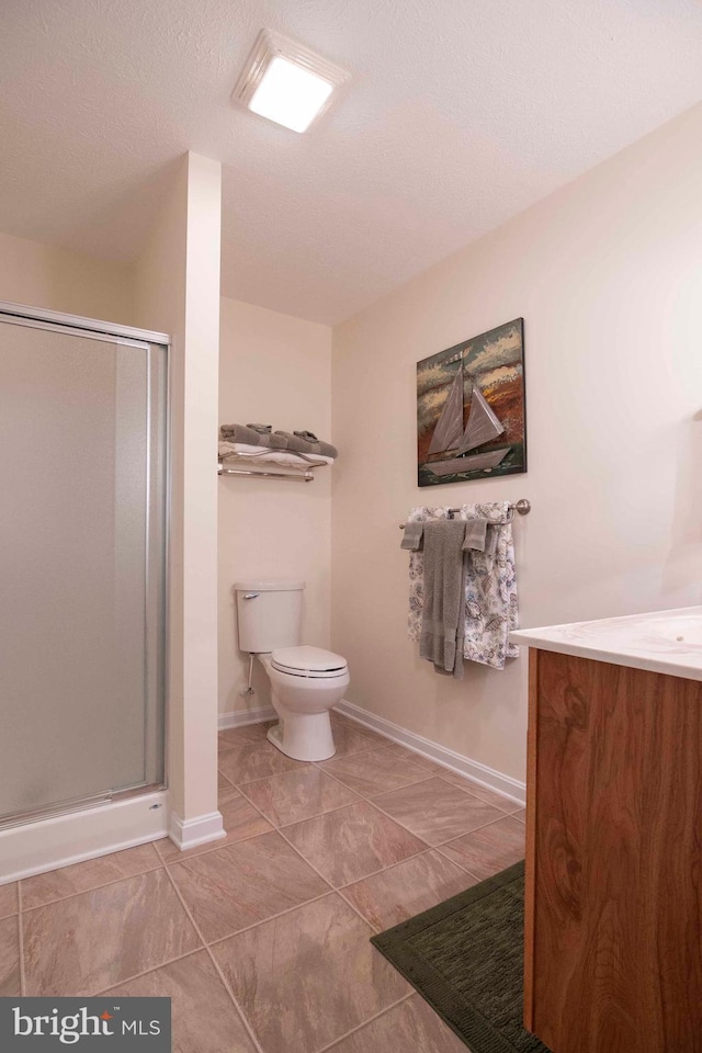 bathroom featuring a stall shower, baseboards, toilet, a textured ceiling, and vanity