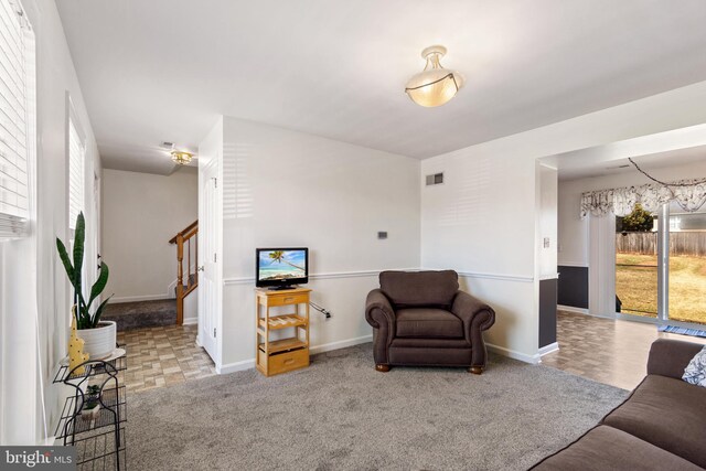 carpeted living room with stairway, baseboards, and visible vents