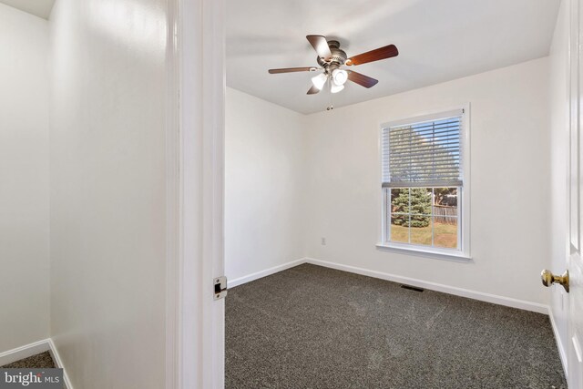 empty room featuring visible vents, baseboards, and dark colored carpet